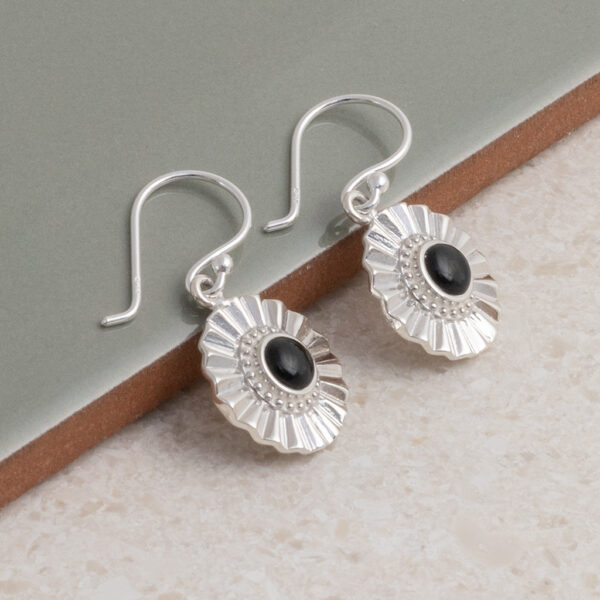 Sterling silver Onyx sun disc earrings on a green title background.