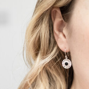 Sterling silver Onyx sun disc earrings worn by model with blonde curly hair.