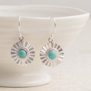Sterling silver Turquoise sun disc earrings set on a shell background.