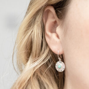 Sterling silver Turquoise sun disc earrings worn by a model with blonde curly hair.