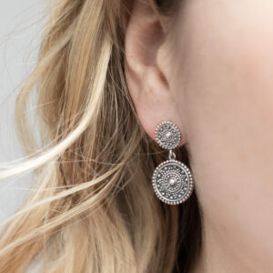 Sterling silver oxidised double Marrakech stud earrings with intricate detailing and a darkened antique finish worn by a model with blonde highlighted curly hair.