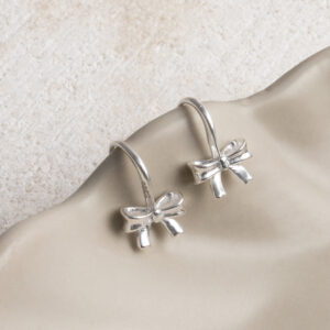Sterling Silver Bow Drop Earrings on a wavy creamy background.