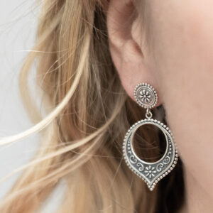 Sterling silver Harbala dangly stud earrings featuring Moroccan design with elegant hoop drop detailing with a model with blonde curly hair.