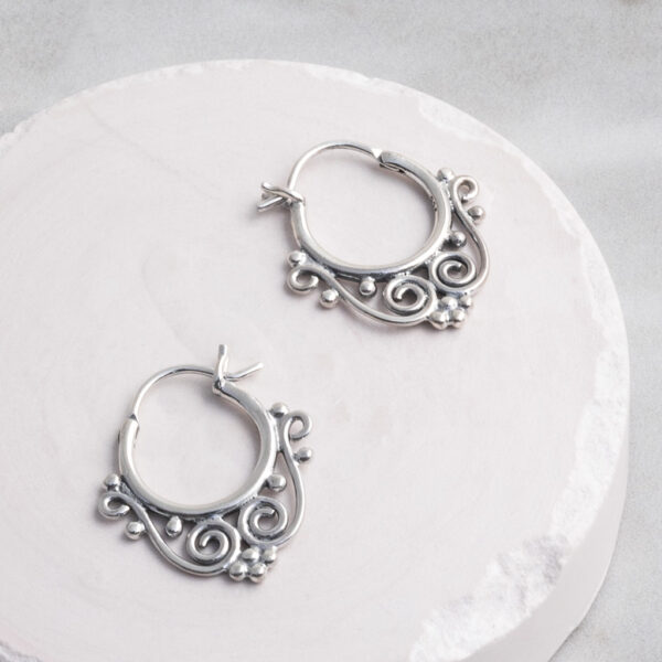 Sterling silver Safi hoop earrings featuring a handcrafted detailing on a white circle prop.