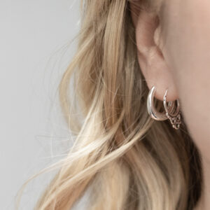 Sterling Silver Tarfaya Hoops featuring a handcrafted detailing worn by a model with blonde curly hair.
