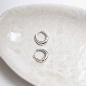 Sterling Silver Oval Huggies on stone background