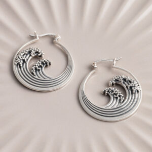 Sterling silver hoop earrings inspired by the iconic Great Wave off Kanagawa, featuring intricate oxidised detailing to highlight the wave’s movement and texture on a cream shell background.