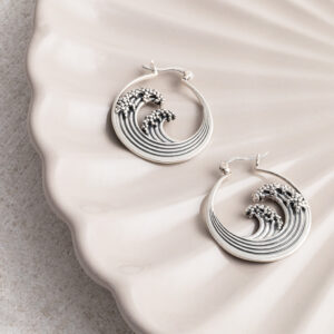 Sterling silver hoop earrings inspired by the iconic Great Wave off Kanagawa, featuring intricate oxidised detailing to highlight the wave’s movement and texture on a cream shell background.