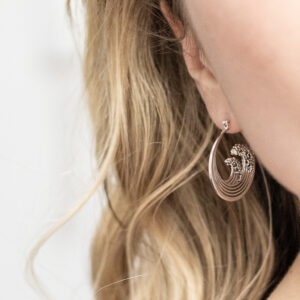 Sterling silver hoop earrings inspired by the iconic Great Wave off Kanagawa, featuring intricate oxidised detailing to highlight the wave’s movement and texture worn by a model with curly blonde hair.