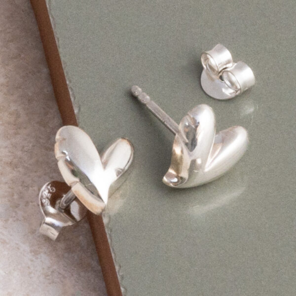 Sterling Silver Love Heart Studs on sage green tile background.