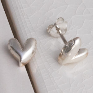 Sterling Silver Love Heart Studs on white tile background.