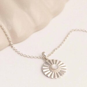 Sterling silver Mother of Pearl sun disc necklace on a white and shell background.