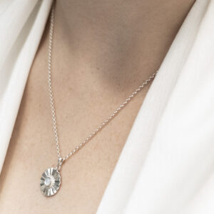Sterling silver Mother of Pearl sun disc necklace worn by a model.
