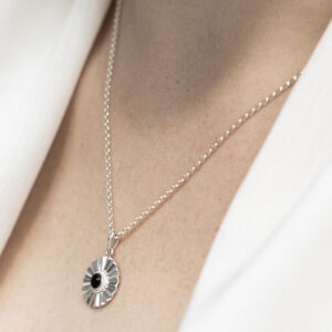 Sterling silver Onyx sun disc necklace worn on a model.