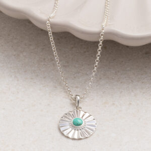 Sterling silver Turquoise sun disc necklace set on a shell background.