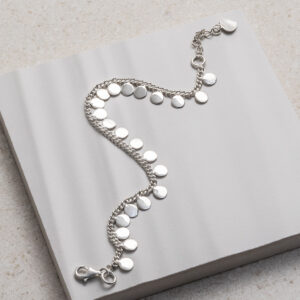 Sterling Silver Sequin Charm Bracelet on a white tile background.