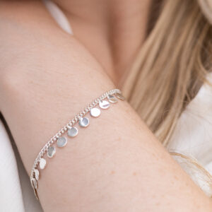 Sterling Silver Sequin Charm Bracelet on a cream tile background worn by a model.