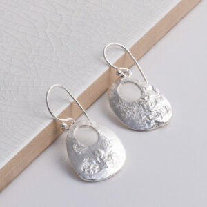 Sterling Silver Molten Dangly Earrings on a white tile background.