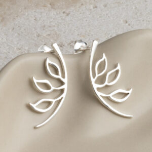 Sterling Silver Leaf Silhouette Studs on a creamy wavy background.