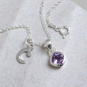 Sterling Silver Amethyst Birthstone Necklace on a tile with letter charms