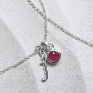 Sterling Silver Ruby Birthstone Necklace on a tile with a letter add on charm