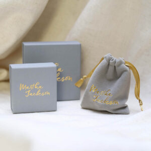 Grey Martha Jackson Gift box and pouch with gold logo on a textile