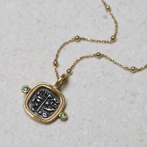 Gold Plated Sterling Silver Hieroglyphics Square Necklace on beige fabric background.