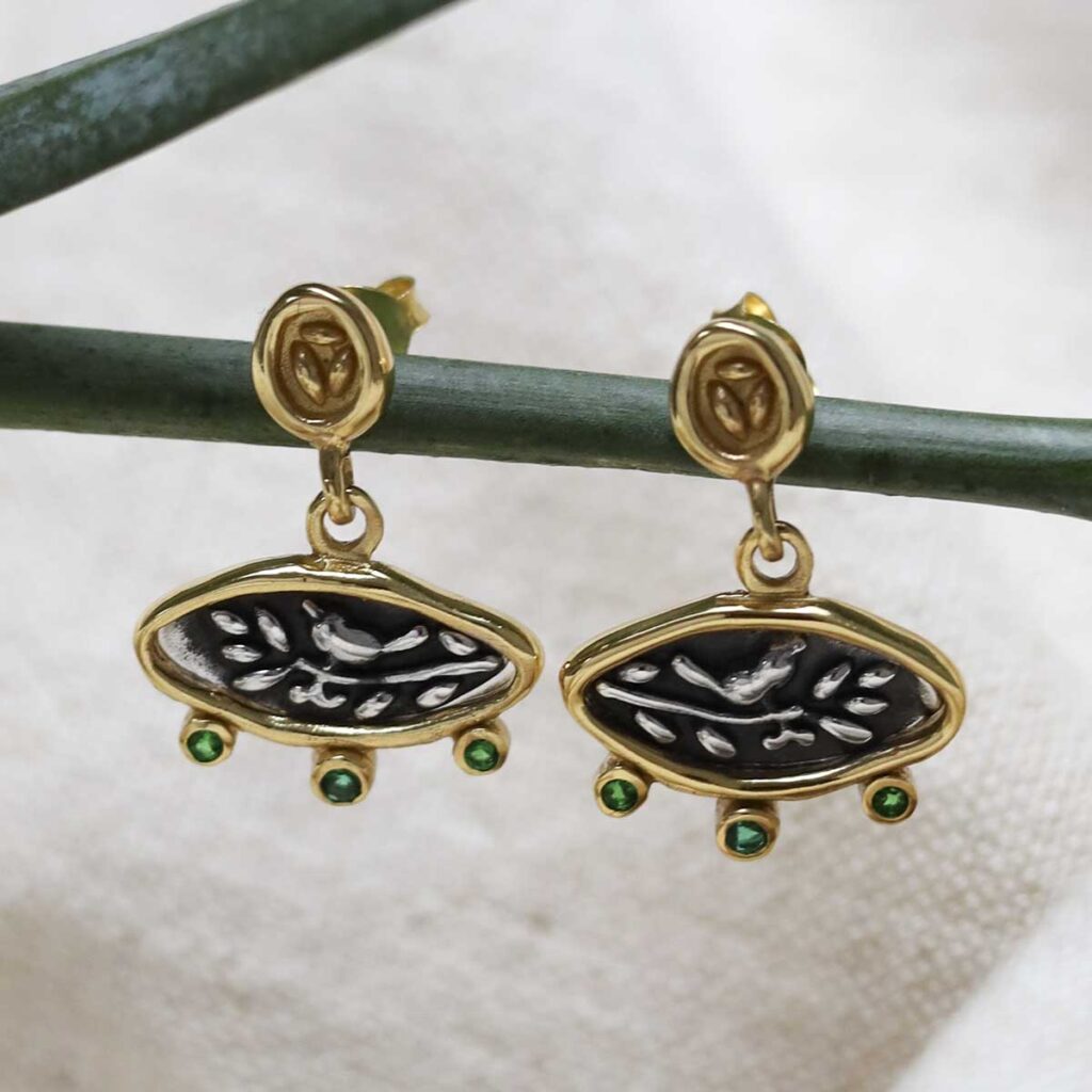 Gold Plated Sterling Silver Hieroglyphics Earrings on a beige fabric background.