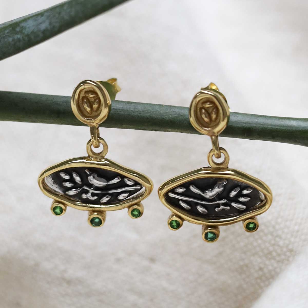 Gold Plated Sterling Silver Hieroglyphics Earrings on a beige fabric background.