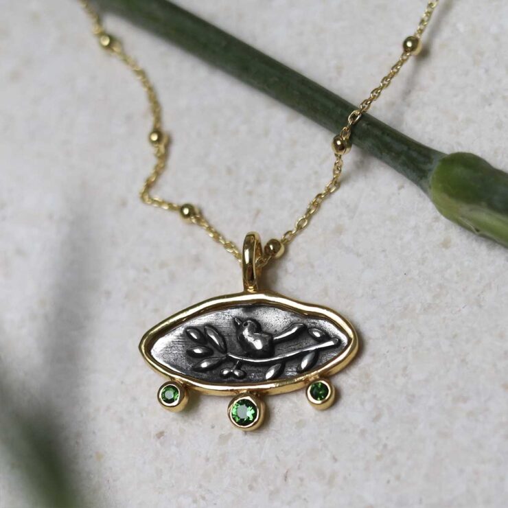 Gold Plated Sterling Silver Hieroglyphics Necklace on beige fabric background.