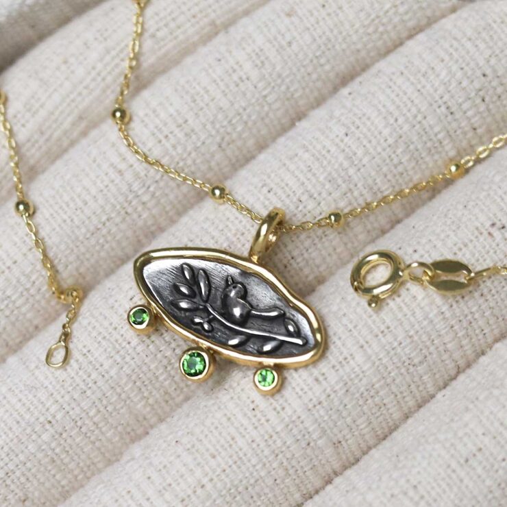 Gold Plated Sterling Silver Hieroglyphics Necklace on beige fabric background.