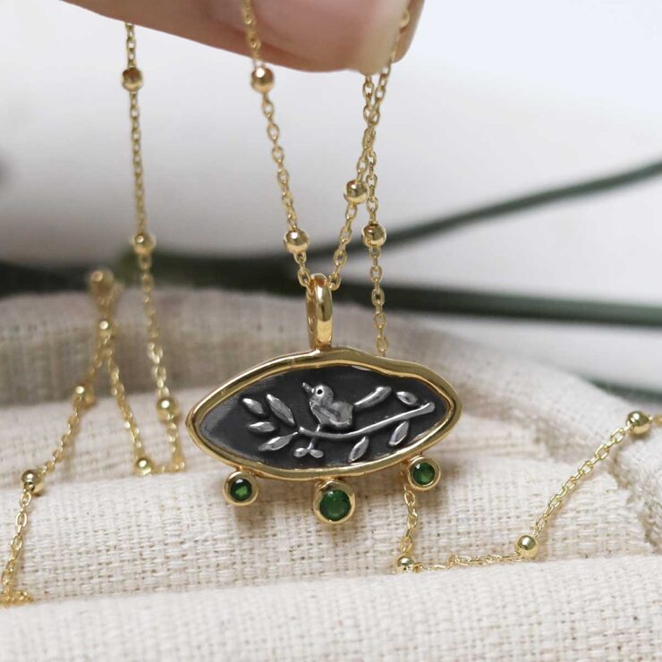 Gold Plated Sterling Silver Hieroglyphics Necklace on beige fabric background.