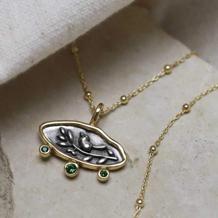 Gold Plated Sterling Silver Hieroglyphics Necklace on beige fabric background.