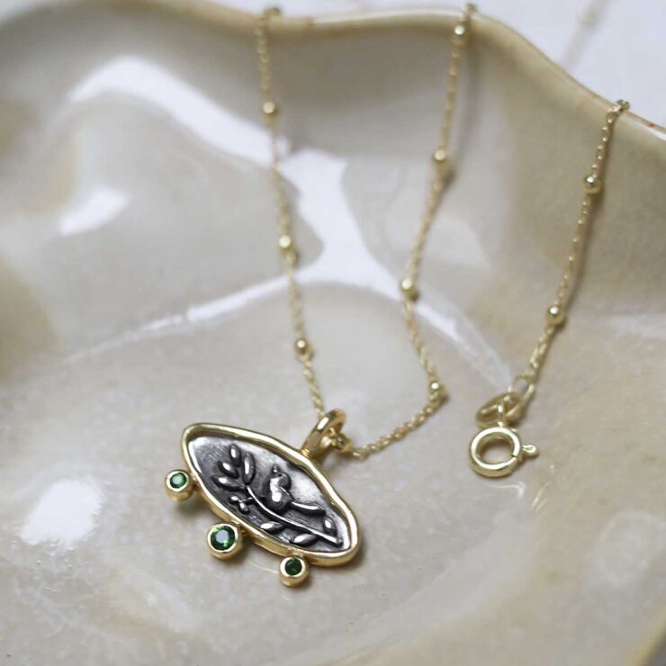 Gold Plated Sterling Silver Hieroglyphics Necklace on beige fabric background.