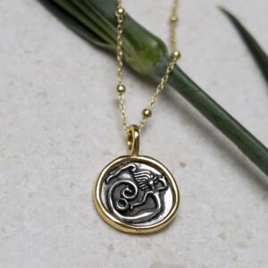Gold Plated Sterling Silver Mermaid Necklace on beige background with green stem leaf.