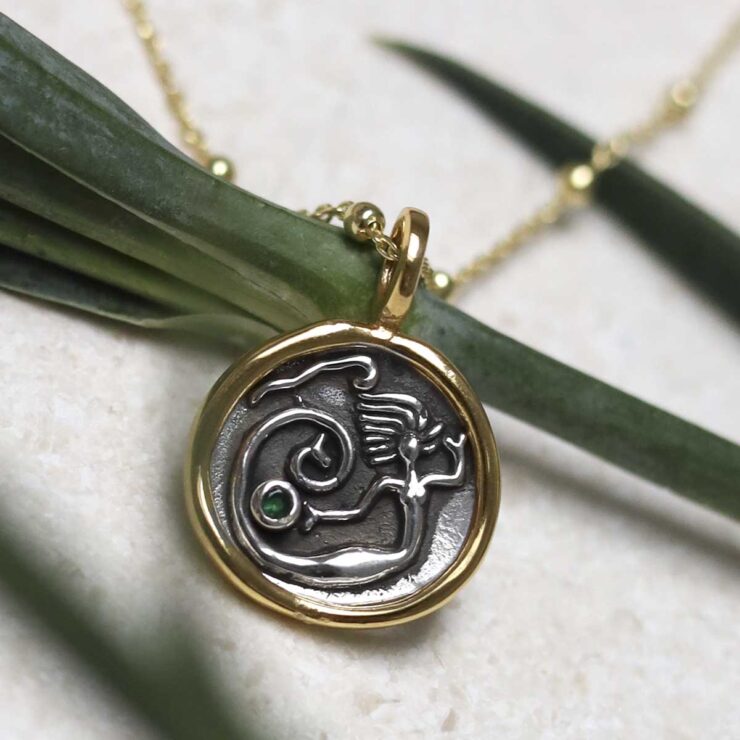 MZB151_Gold Plated Sterling Silver Mermaid Necklace_2 Gold Plated Sterling Silver Mermaid Necklace on beige background with green stem leaf.