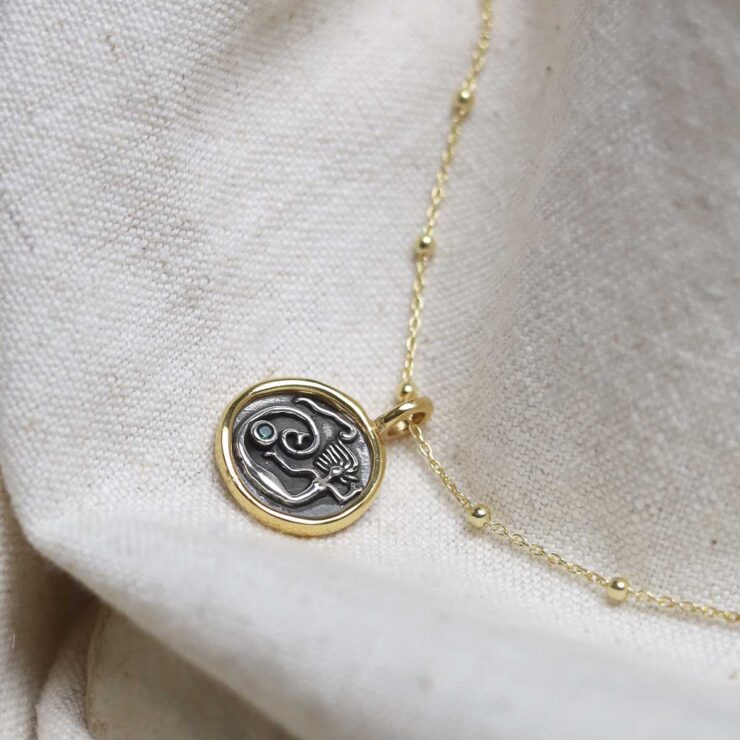 Gold Plated Sterling Silver Mermaid Necklace on beige background