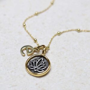 Gold Plated Sterling Silver Lotus Necklace with initial 'e' charm on a beige background.