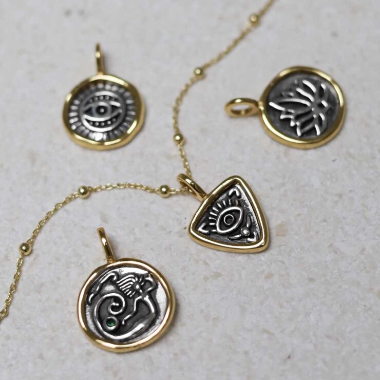 Gold Plated Sterling Silver Evil Eye Necklace group on beige fabric background.
