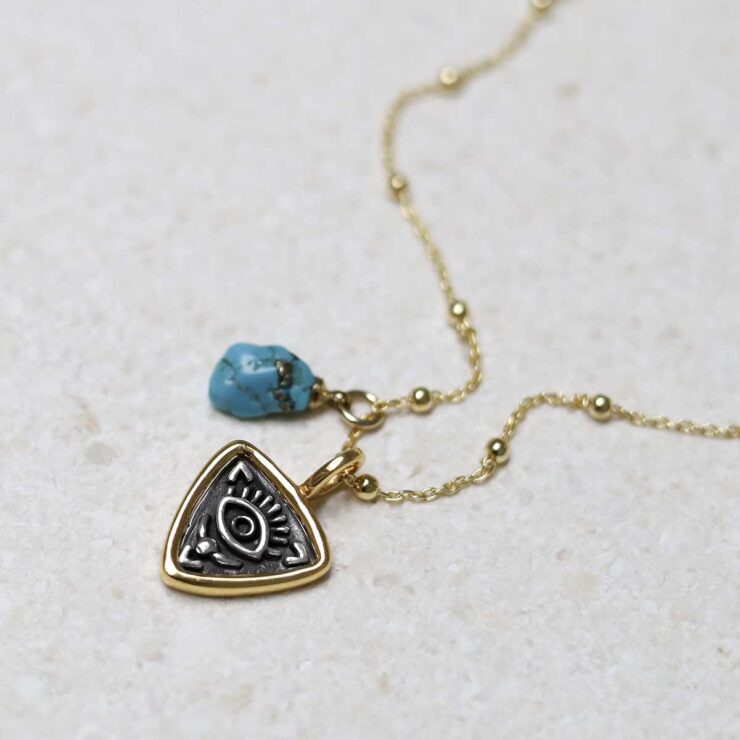 Gold Plated Sterling Silver Evil Eye Necklace on beige fabric background with turquoise charm